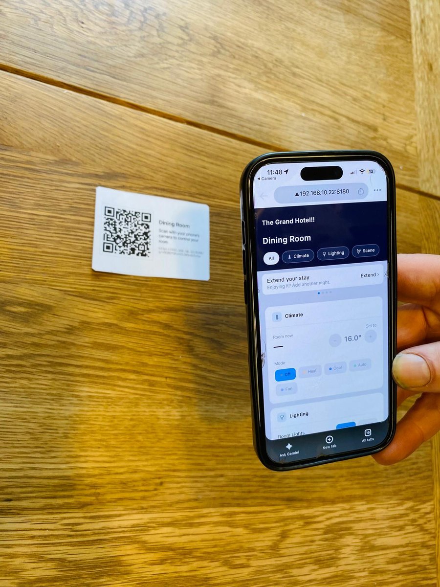 A printed QR card for a location, beside a phone showing that location's controls after scanning it